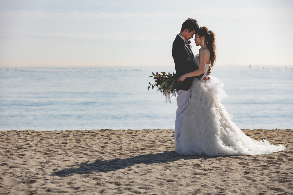 フォトウェディングロケーション撮影 砂浜で抱き合う新郎新婦