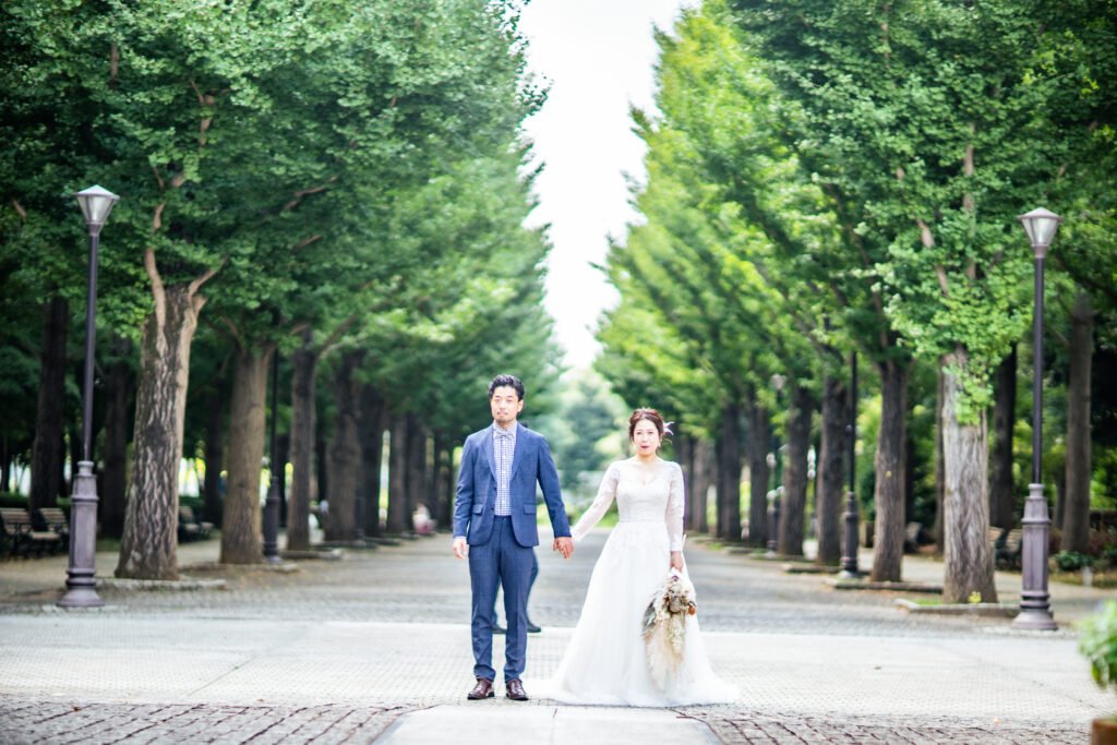 新緑の並木道でタキシードとウェディングドレスを着た新郎新婦